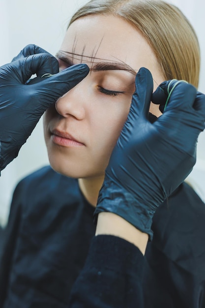 Young woman during professional eyebrow mapping procedure before permanent makeup