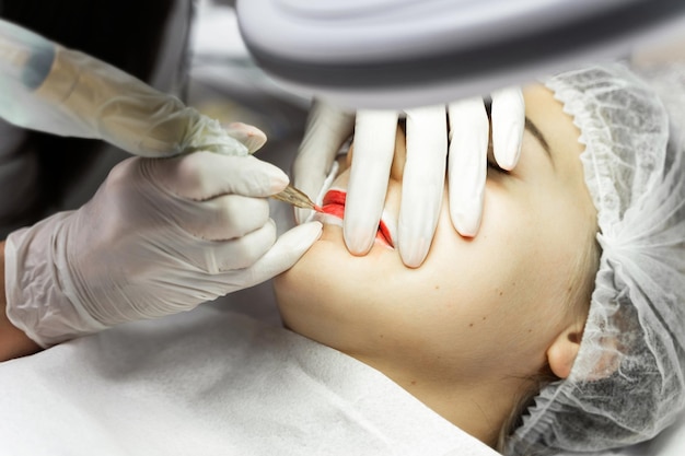 Young woman during professional permanent makeup procedure lip blushing