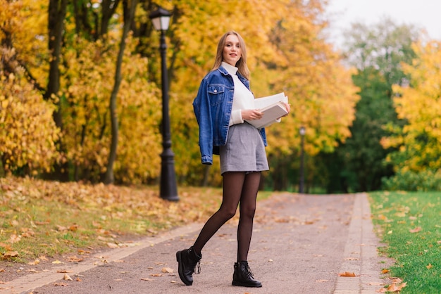 Young woman protecting from corona virus when walking in park. Autumn background.