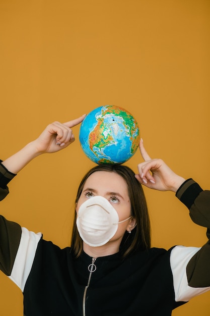 Young woman in protective face mask holding globe