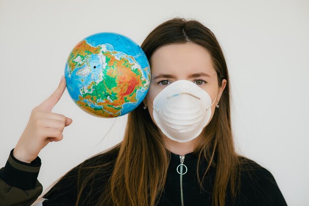 Young woman in protective face mask holding globe