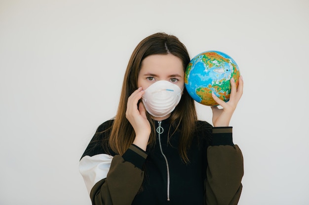 Young woman in protective face mask holding globe