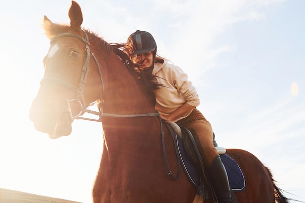 Молодая женщина в защитной шляпе со своей лошадью в сельском хозяйстве в солнечный день