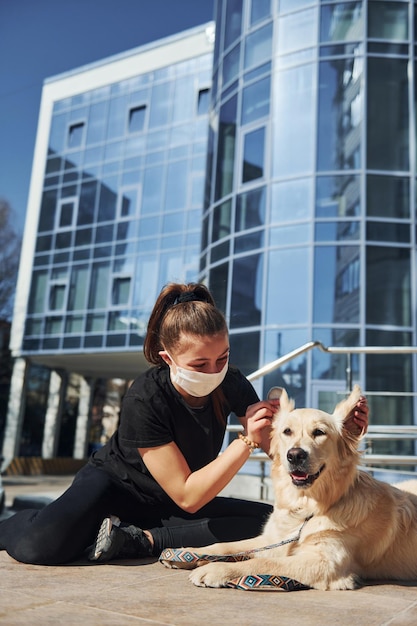 Young woman in protective mask have a walk outdoors near business building at quarantine time Conception of coronavirus