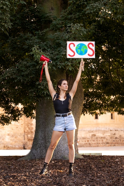 Молодая женщина протестует с знаком sos против изменения климата