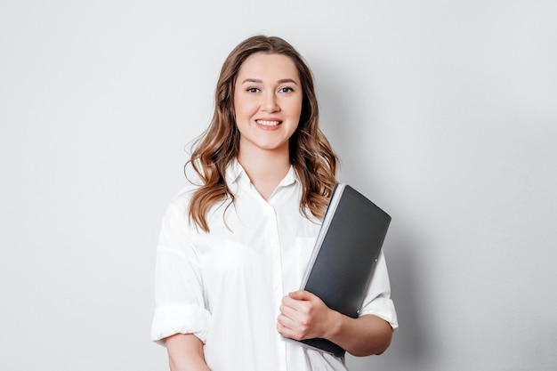 Young woman psychologist holding a folder in her hands looking at camera and smiling