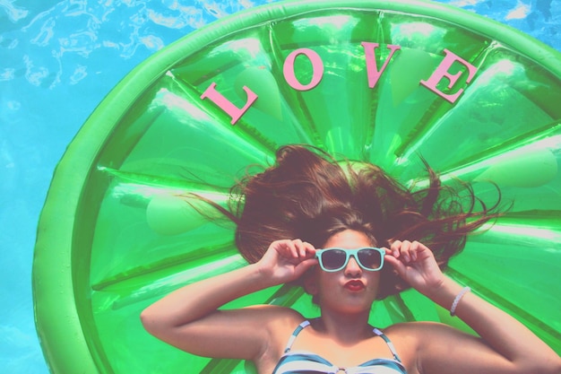 Young woman puckering while lying on inflatable raft at swimming pool