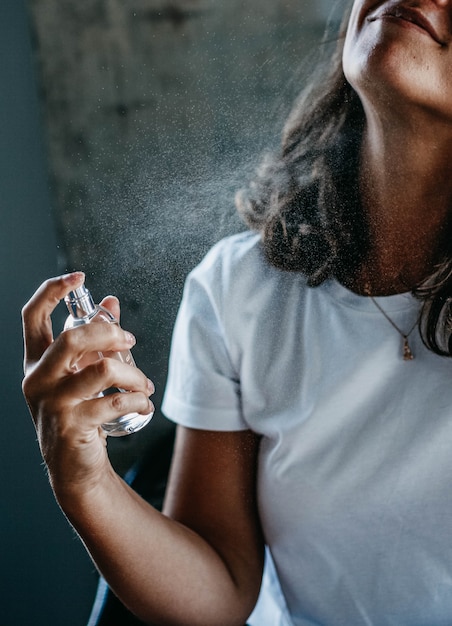 young woman puffs perfume in a bottle and enjoys the scent