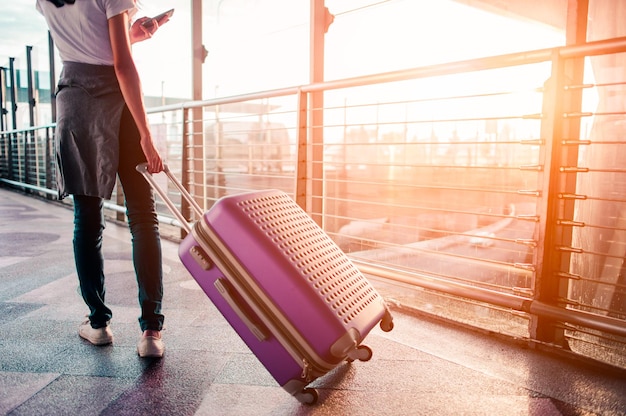 Young woman pulling suitcase in  airport terminal. Copy space