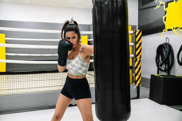 Young woman punching bag in gym