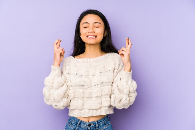 Young  woman on a purple crossing fingers for having luck