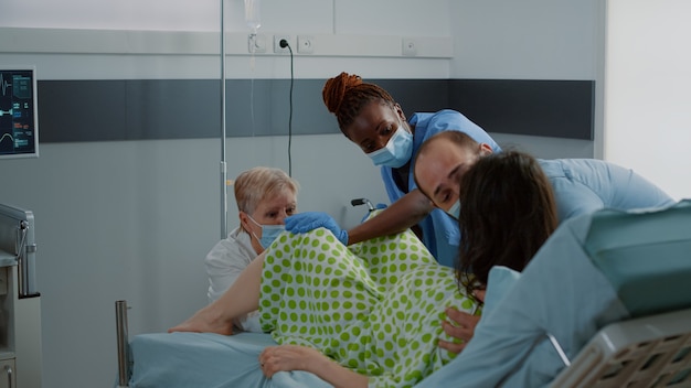 Young woman pushing while giving birth to child in hospital ward