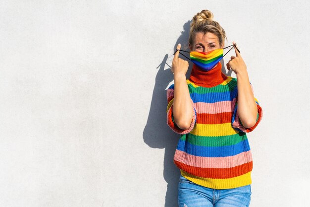 Young woman put off gay pride face mask during Coronavirus pandemic in rainbow colors symbol of Lgbtq social movement concept image with copyspace for your individual text