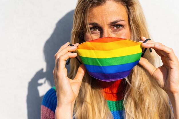 Young woman put off gay pride face mask during Coronavirus pandemic in rainbow colors symbol of Lgbtq social movement concept image