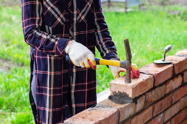 A young woman puts a brick on cement mortar