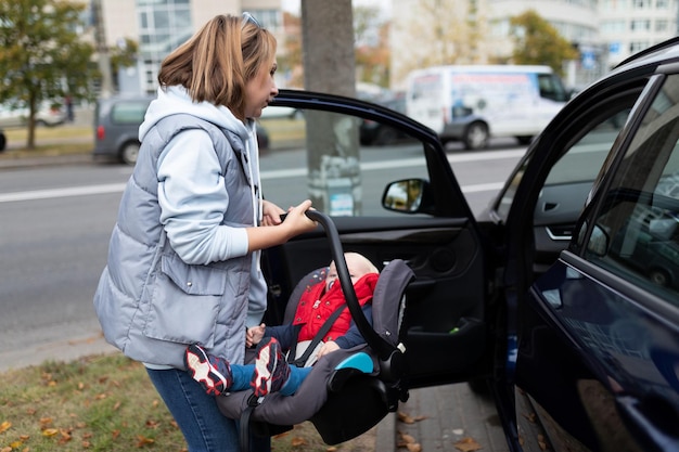 1歳児用のチャイルドシートを車に乗せる若い女性