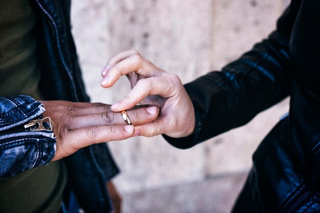 Foto una giovane donna mette un anello nuziale sulla mano di un uomo. sposi al matrimonio.una bella tradizione di coppie innamorate.