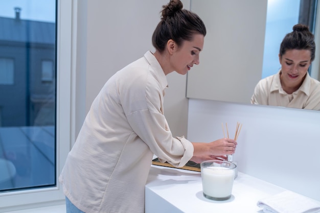 A young woman putting air freshener in the bathroom