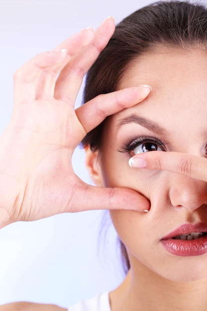 Young woman putting contact lens in her eye close up