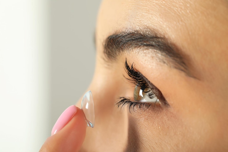 Photo young woman putting contact lens in her eye closeup