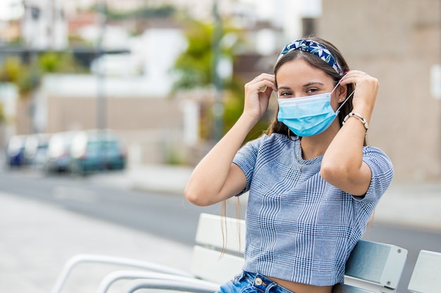 Young woman putting on a face mask while on the street