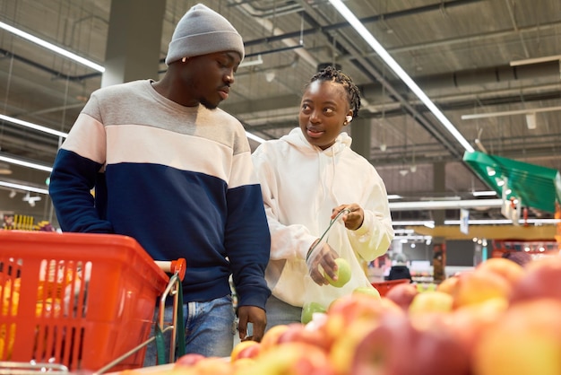 果物を購入しながら新鮮な青リンゴをセロハン袋に入れる若い女性