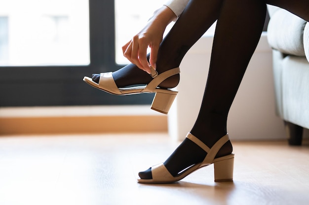 Young woman putting on her heels at home