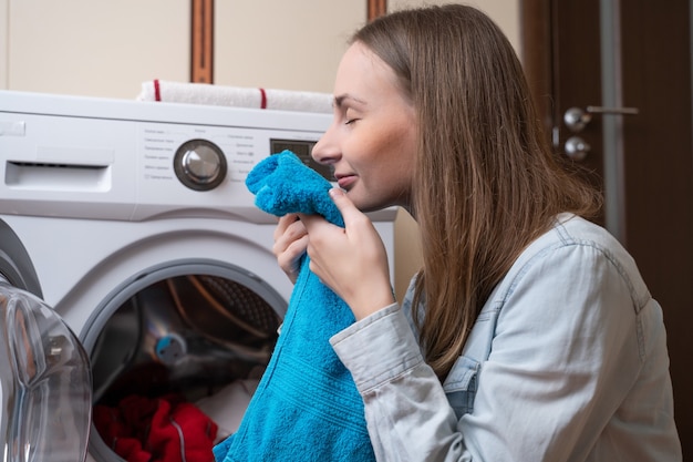 Foto giovane donna che mette il bucato in lavatrice donna che lava il bucato utilizzando la moderna macchina automatica