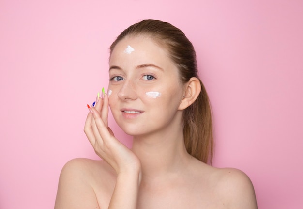 Photo young woman putting on moisturizing cream