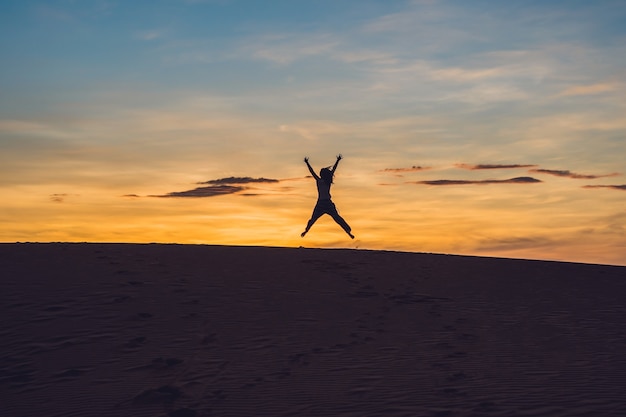 Giovane donna in rad deserto sabbioso al tramonto o all'alba