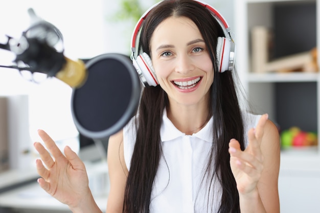 Young woman radio presenter smiling in front of microphone. Broadcasting concept