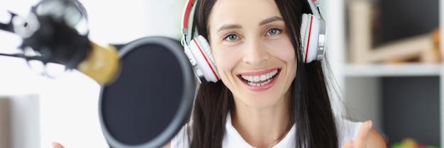 Young woman radio presenter smiling in front of microphone