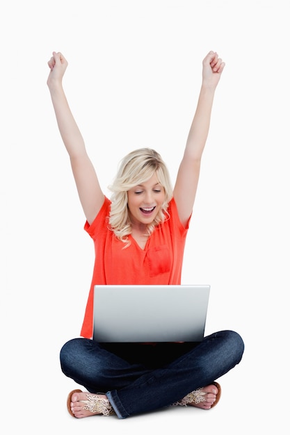 Photo young woman raising her arms in success in front of her laptop