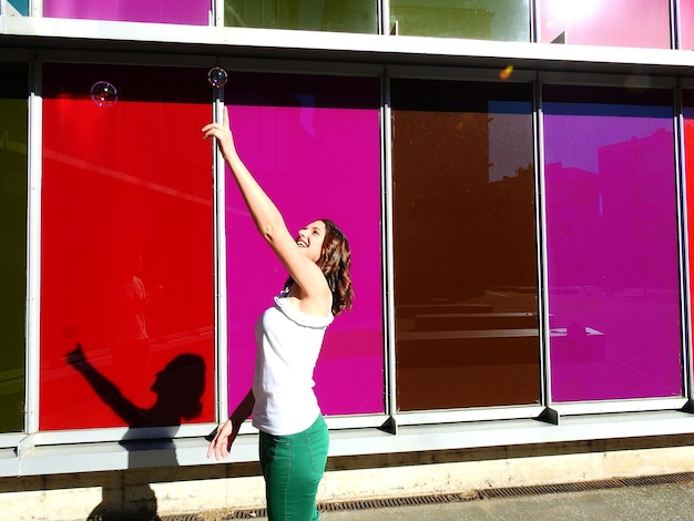 Foto giovane donna che si avvicina alla bolla mentre si trova accanto a un edificio colorato