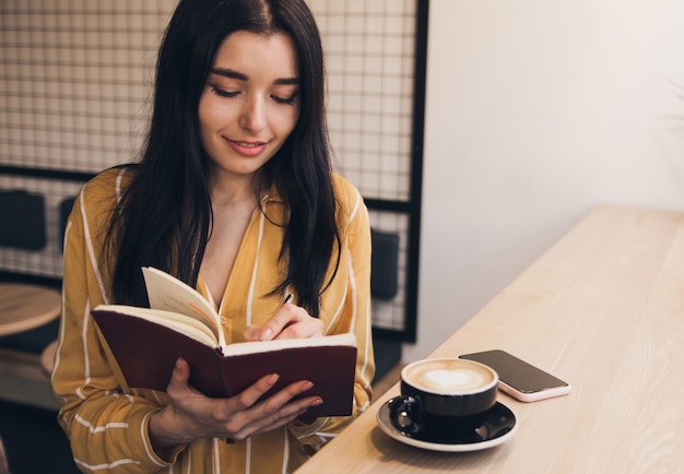La giovane donna ha letto il libro e beve il caffè in caffè