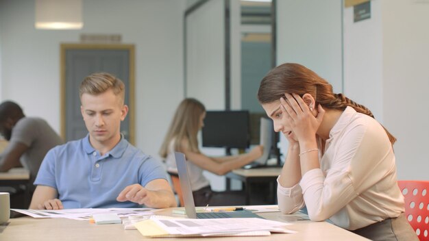 Foto giovane donna che legge cattive notizie sul computer portatile al coworking