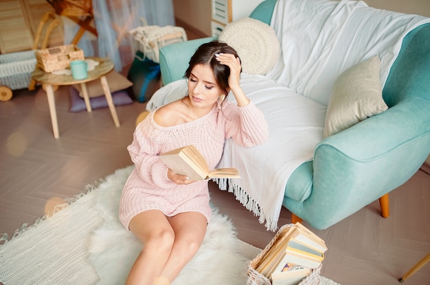 Young woman reading a book and holding cup of coffee