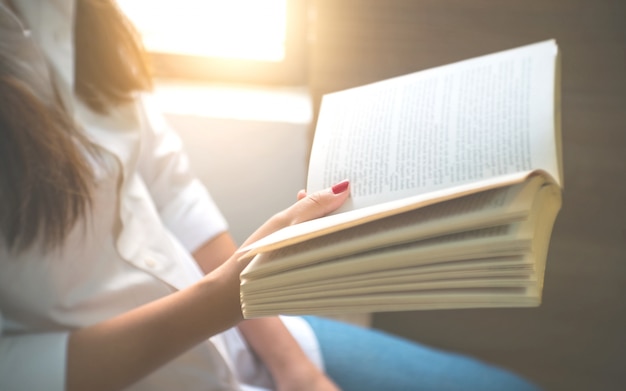 Giovane donna che legge un libro a casa.