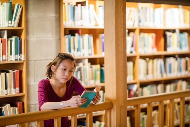 Young woman reading book in library