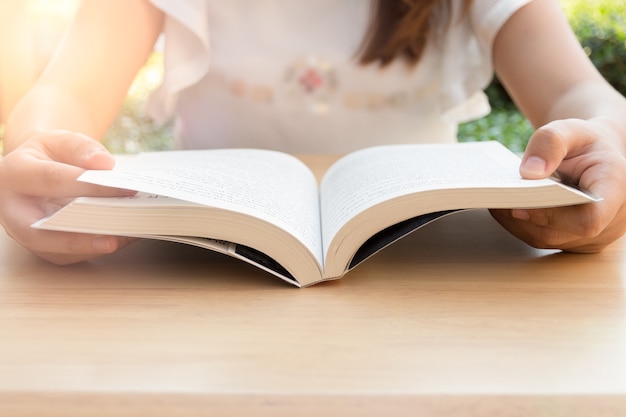 Giovane donna che legge un libro nel parco sotto la luce del sole