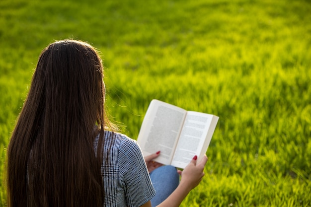 公園で本を読んでいる若い女性