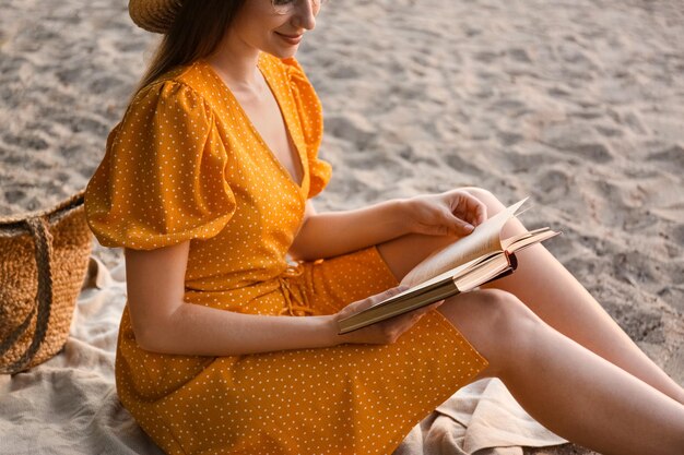 Young woman reading book on sandy beach