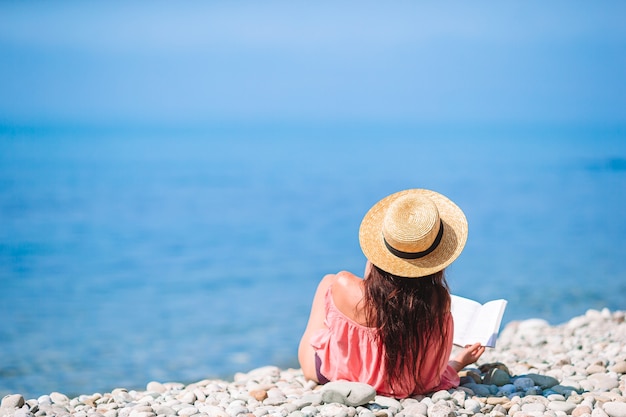 Young woman reading book during tropical white beach