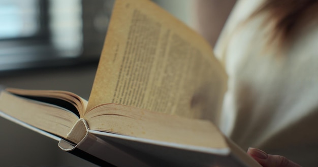 Foto giovane donna che legge un libro seduta sul divano a casa. è bello trascorrere il tempo libero nel fine settimana.