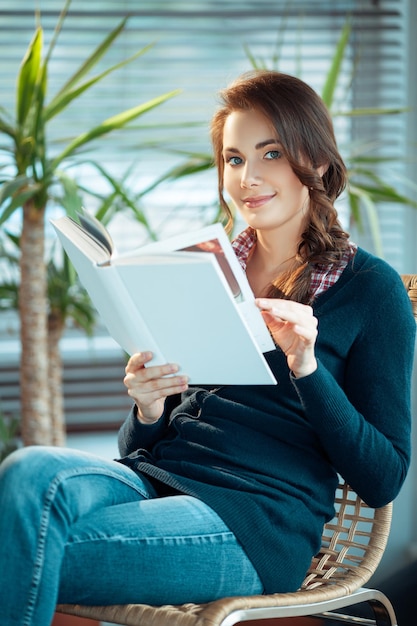 Photo young woman reading a book with a blank cover