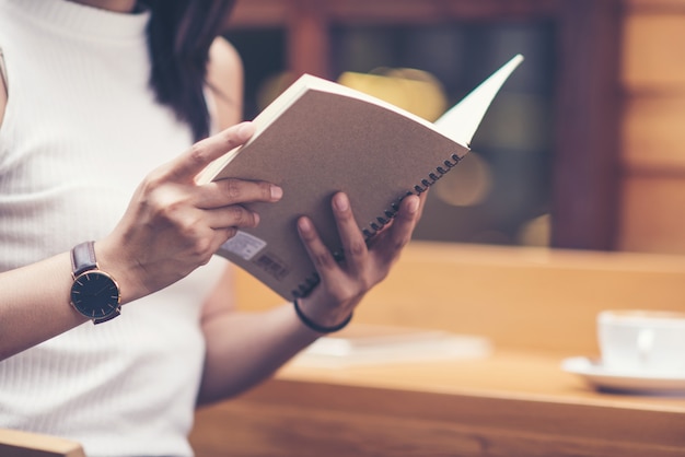 Photo young woman reading a book with cup of coffee