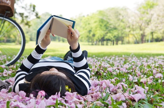 Young woman reading booklet on grass in the garden