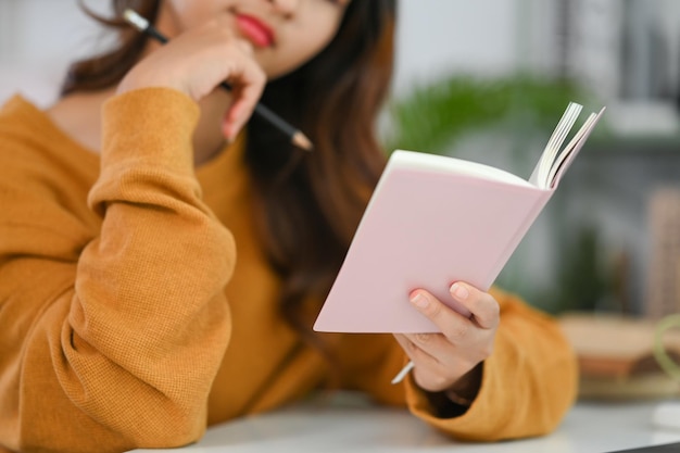 Young woman reading journal or checking working schedule plan at desk