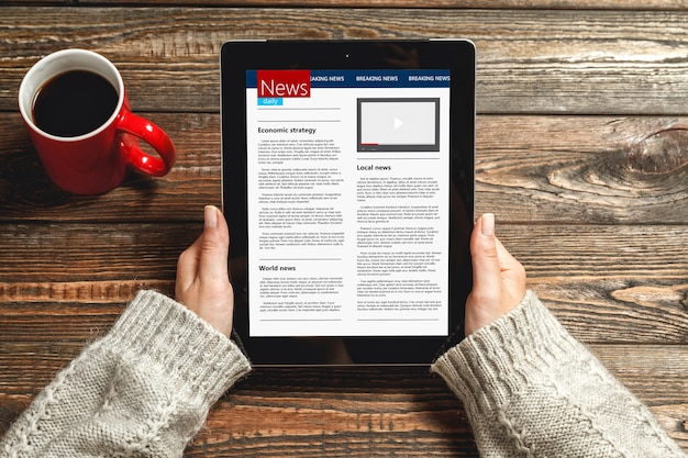 Young woman reading news using tablet at home