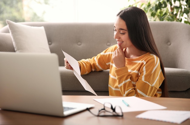 Young woman reading paper letter at home